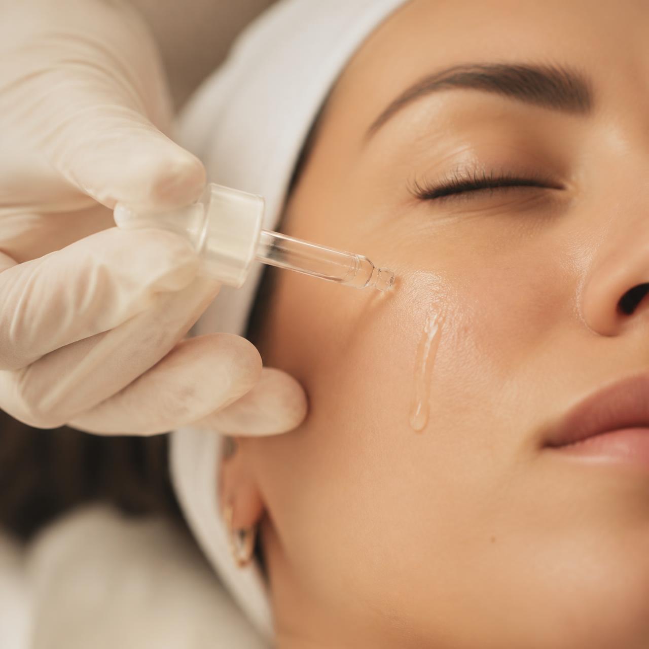Hudterapeut applicerar serum under en ansiktsbehandling hos SI Beauty